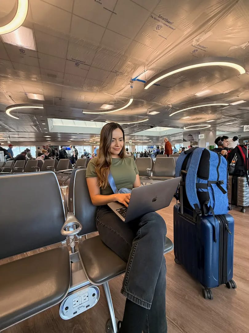 caro trabajando con equipaje de mano y mochila - Apps para viajar que usamos Caro y Juanfe en cada viaje